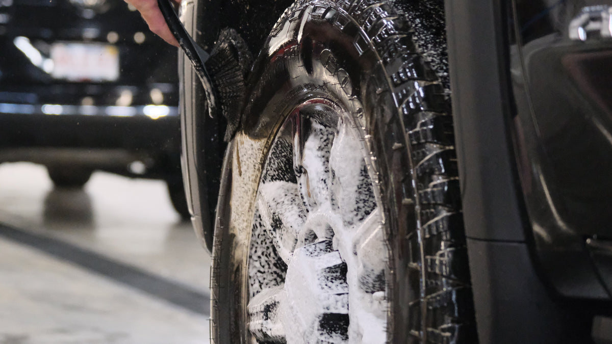Wheel being cleaned with tire scrub brush.