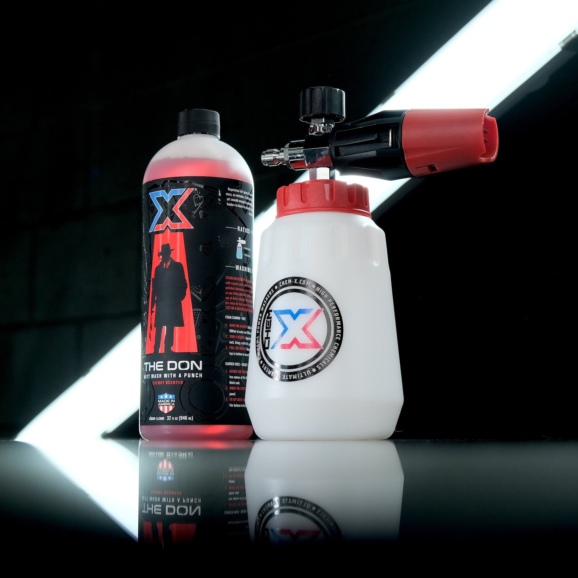 A 32oz bottle of red mitt wash called The Don and a white foam cannon with a red cap and nozzle, both branded with a Chem-X logo, displayed on a reflective black surface against a dark background with bright light beams.