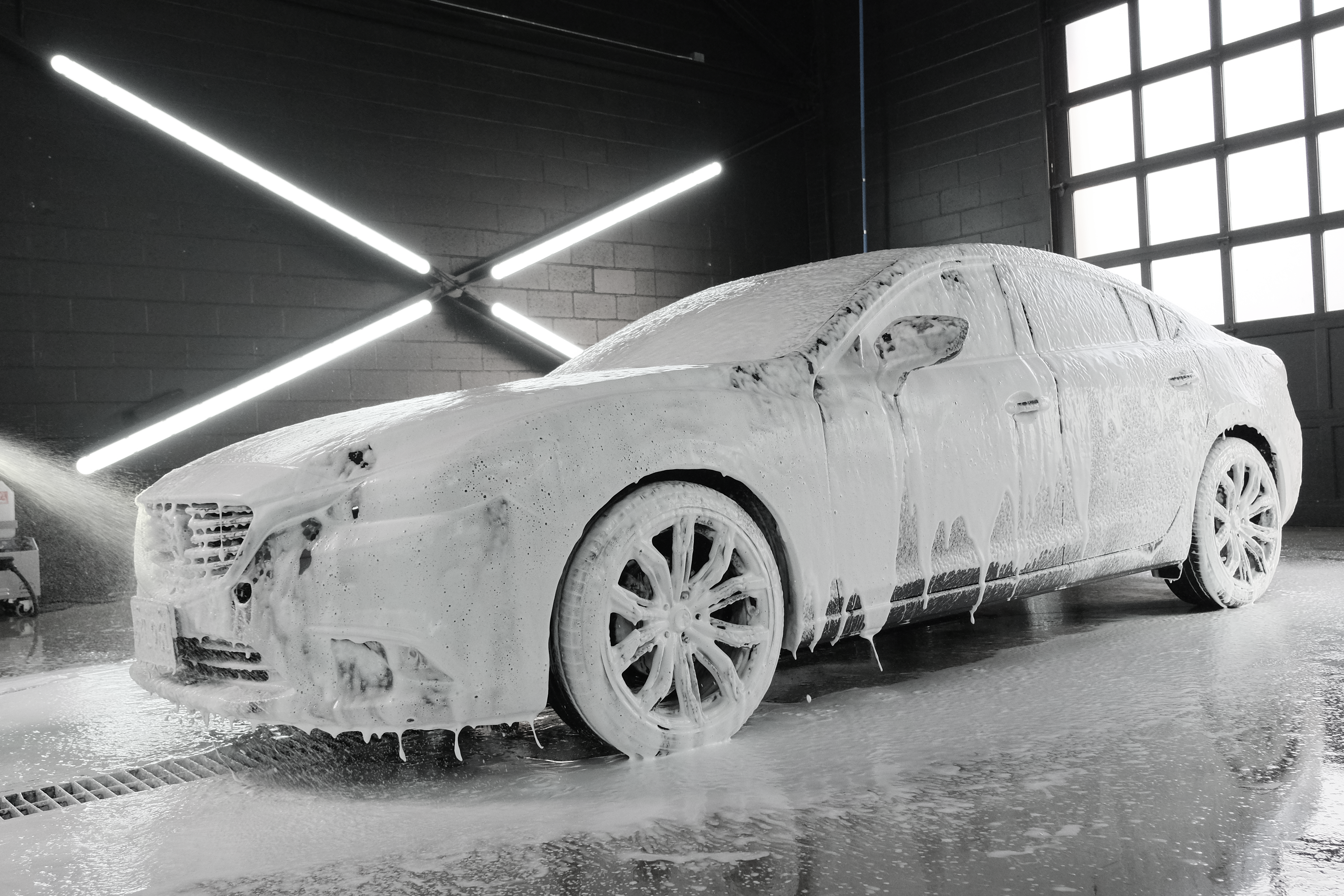 Car covered in foam in wash bay.