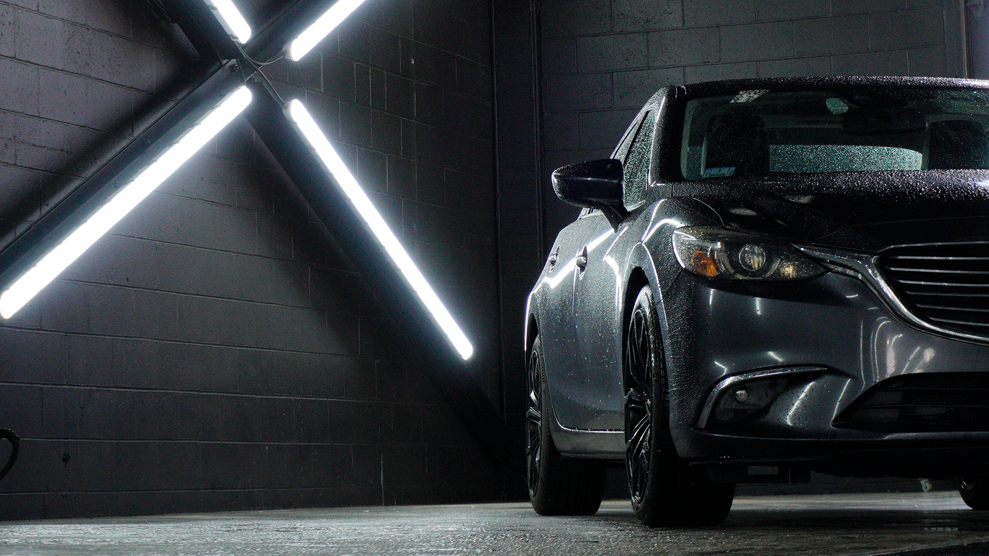Car parked in a dark garage with neon lights on the wall