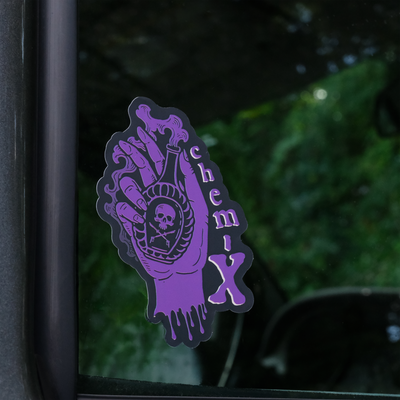 A purple sticker with a hand holding a potion with a skull on it on the front passenger window of a truck.