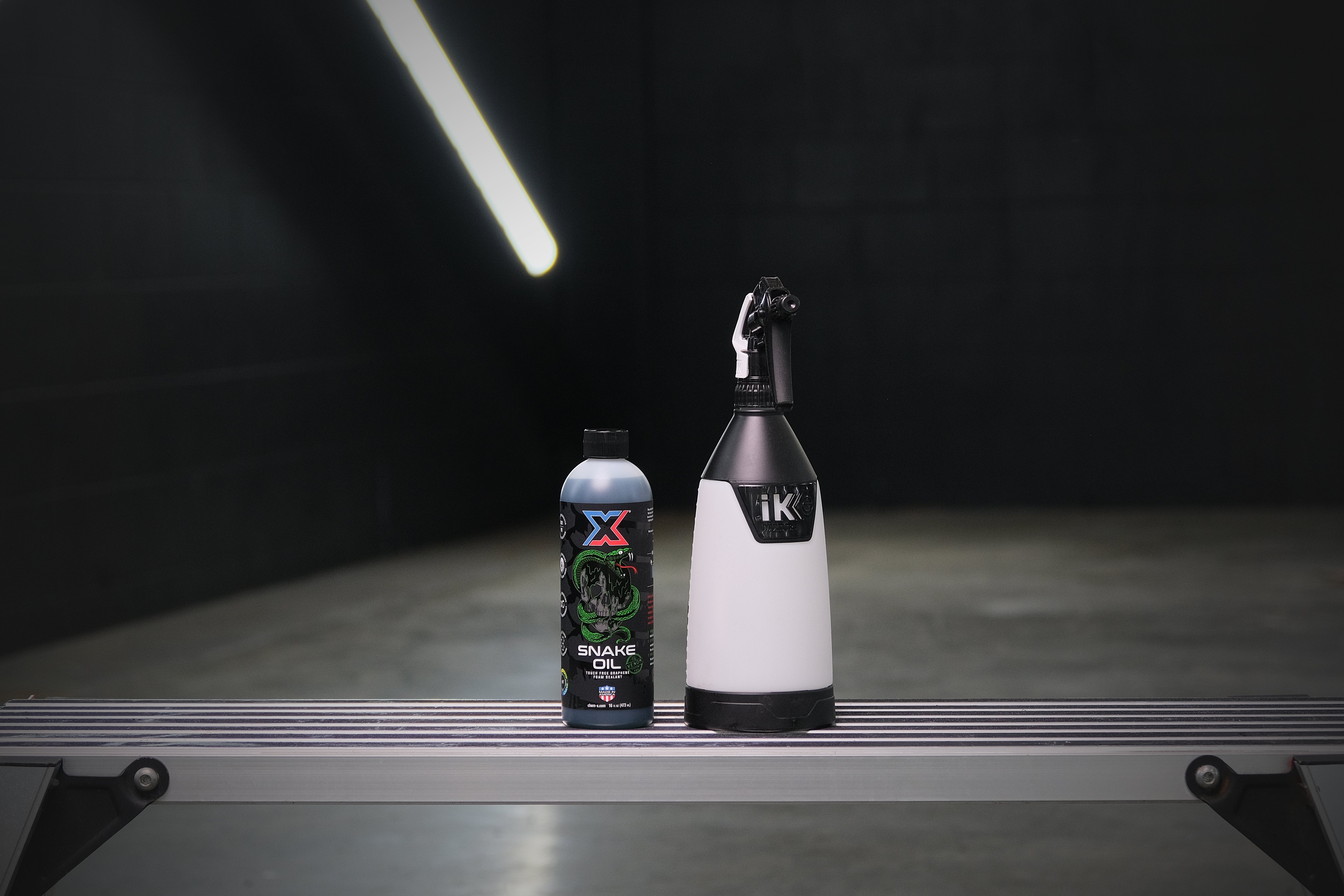 Snake Oil Venom 16oz and iK Multi TR 360 Trigger Sprayer on a reflective surface with a dark background.
