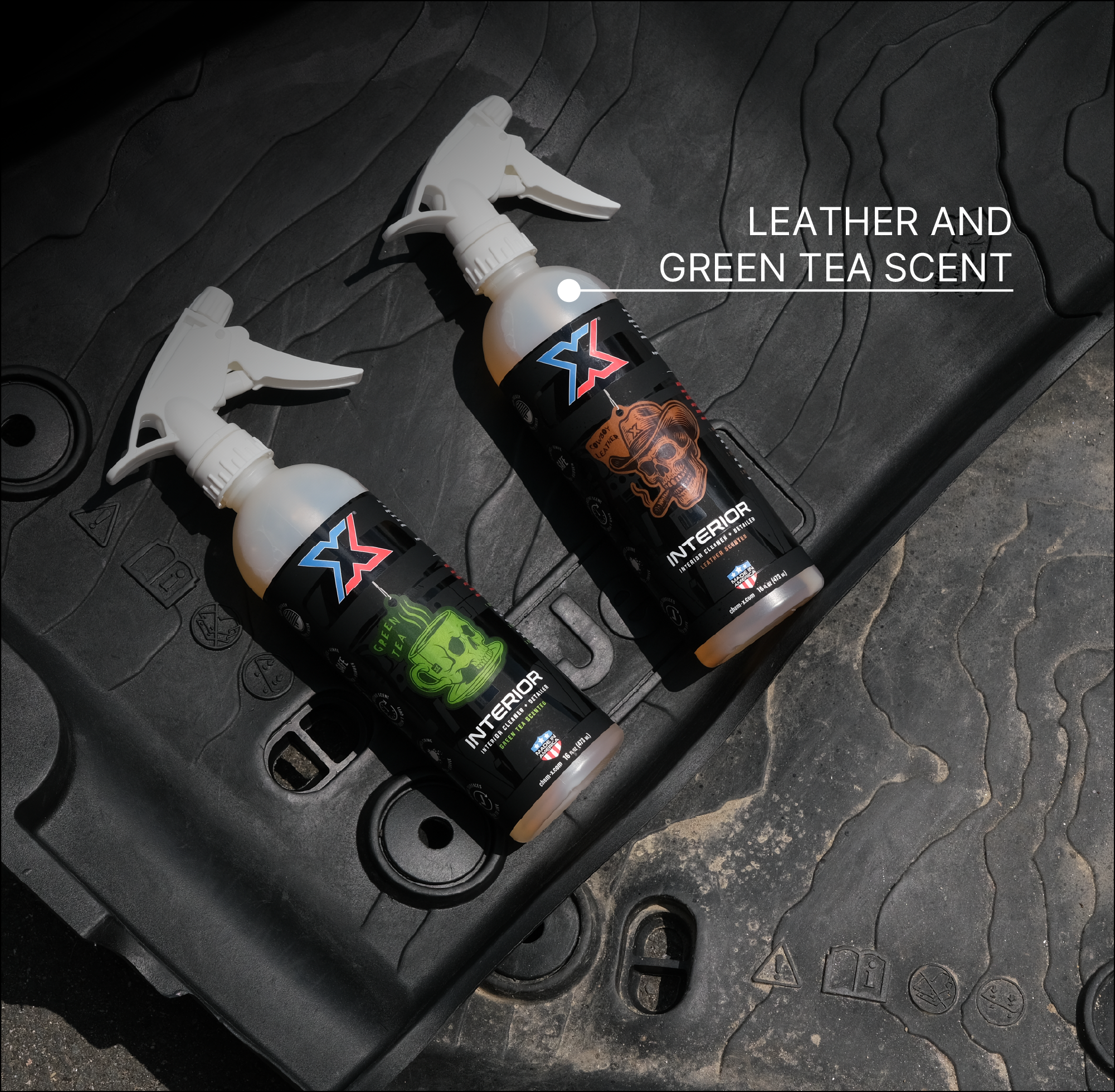 Two spray bottles of orange interior cleaner and detailer leather and green tea scent called Interior placed on a black textured vehicle floor mat, with the text 'LEATHER AND GREEN TEA SCENT' in the upper right.